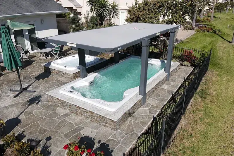 Swimlife swim spa installed in ground with stone around it and a covana spa cover