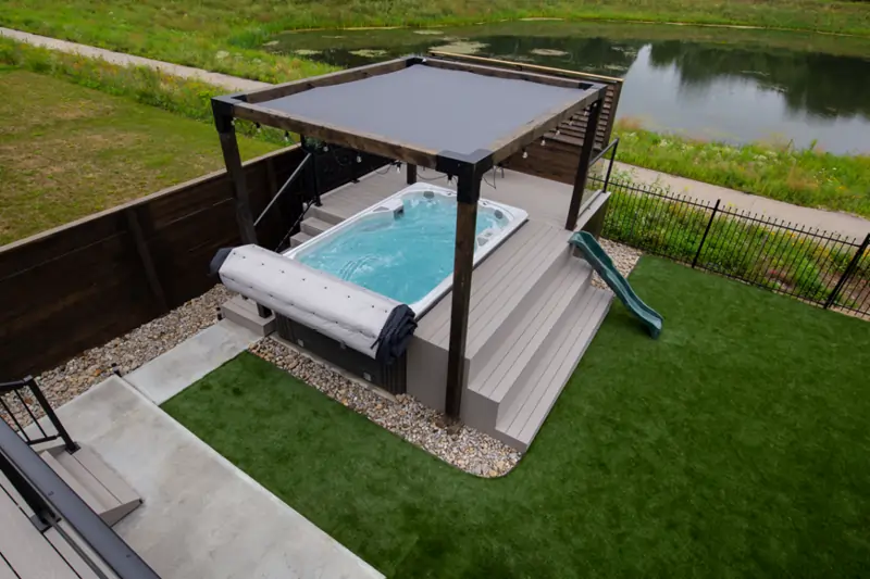 large shot of swim spa with built in steps and pergola in backyard
